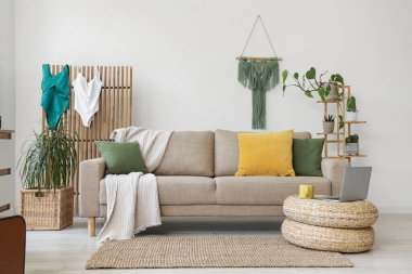 Oturma odasının içinde kanepe, katlanan mayolar ve bitkiler.