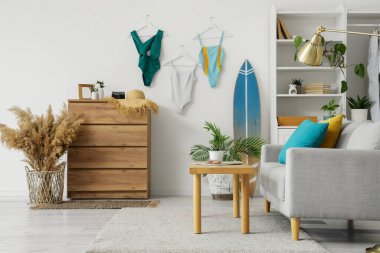 Oturma odasının içinde kanepe, sörf tahtası ve mayo var.