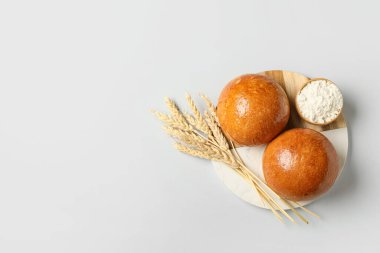 Gri arka planda taze çörekler, un ve buğday kulaklı tahta.