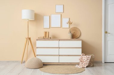 Çekmeceli, zemin lambalı ve boş fotoğraf çerçeveli modern bir oda.