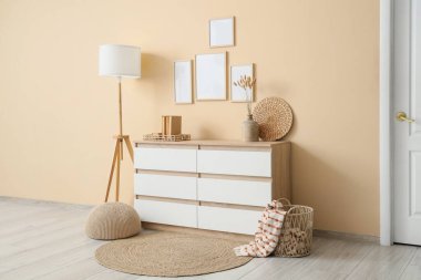 Çekmeceli, zemin lambalı ve boş fotoğraf çerçeveli modern bir oda.