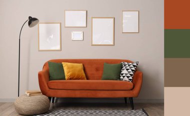 Oturma odasının içinde kahverengi kanepe, standart lamba ve çerçeveler gri duvarda asılı. Farklı renk desenleri