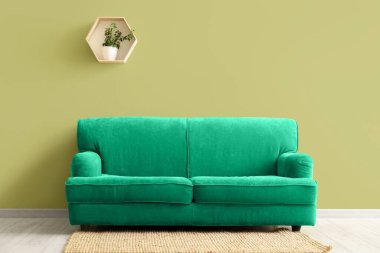 Oturma odasındaki yeşil duvarın yanındaki yumuşak kanepe.