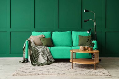 Oturma odasının içinde yeşil kanepe ve kahve masası var.