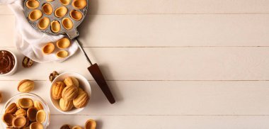 Lezzetli ceviz şekilli kurabiyeler, kaynatılmış süt ve ahşap arka planda beyaz ahşap kabartmalı pişirme formu.