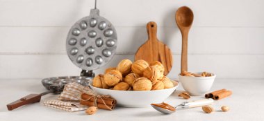 Lezzetli ceviz şekilli kurabiyeler, tarçın, badem ve ahşap masa üzerinde pişirme biçimi olan bir kase.