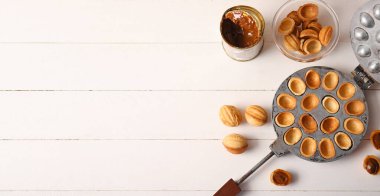 Lezzetli ceviz şekilli kurabiyeler ve beyaz ahşap arka planda kaynamış konserve süt.