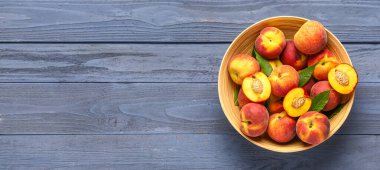 Tatlı şeftalili kase ve mavi ahşap arka planda yapraklar