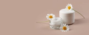 Kavanozlar dolusu doğal krema ve bej arka planda papatya çiçekleri.