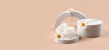 Dekoratif podyumlar bir kavanoz papatya kozmetik kremi ve kahverengi arka planda çiçekler