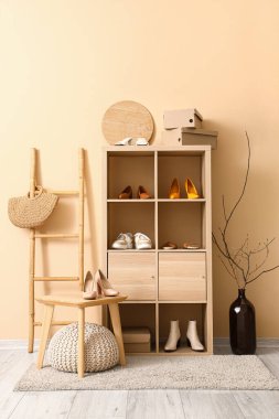 Raflar farklı şık ayakkabılar, merdiven ve tabure butikte bej duvarın yanında.