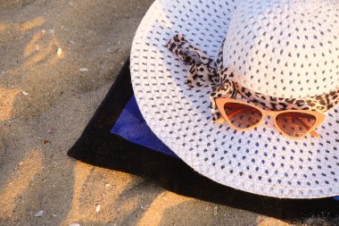 Şık hasır şapkalı ve kumdaki güneş gözlüklü havlu.