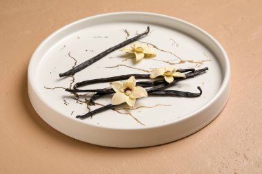 Aromatik vanilyalı tabak ve pembe arka planda çiçekler.