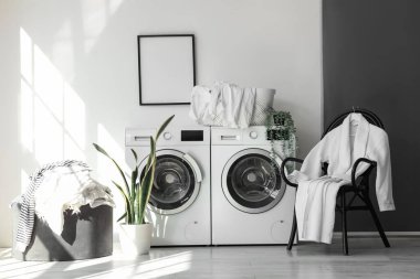 Çamaşır odasının içinde çamaşır makineleri ve kirli çamaşırlarla.