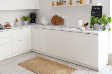 Mutfağın içinde tezgah ve hasır halı var.