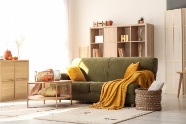 İçinde yeşil kanepe ve balkabağı olan oturma odasının içi.