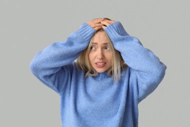 Gri arkaplanda utanç hisseden genç bir kadın