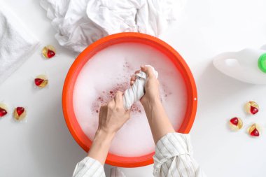 Çamaşırları leğende, beyaz masada suyla yıkayan bir kadın.