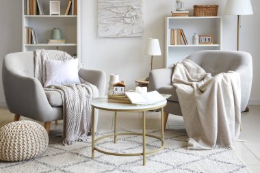 Oturma odasının içinde rahat koltuklar ve sehpanın üzerinde kitaplar var.