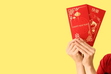 Sarı arka planda zarfları olan genç Asyalı kadın, yakın plan. Çin Yeni Yıl Kutlaması