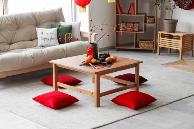 Mandalinalı kahve masası, çay seti ve şenlikli oturma odasında yerde yastıklar. Çin Yeni Yıl Kutlaması