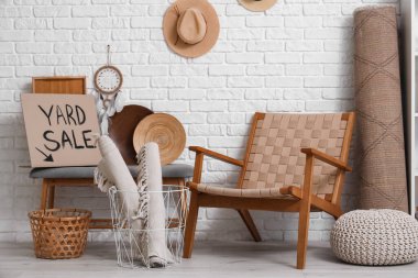 İstenmeyen bir çok şey ve kartondan yazılı YARD satışı odadaki beyaz tuğla duvarın yanında.