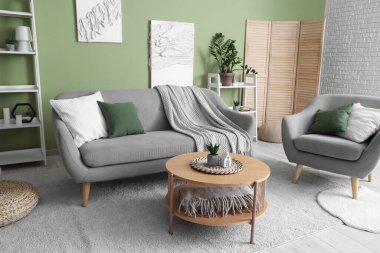 Rahat kanepe, ekose, koltuk ve sehpası olan yeşil oturma odası.