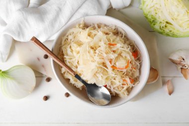 Beyaz ahşap arka planda malzemeler üzerine ev yapımı lahana turşusu, yakın plan.