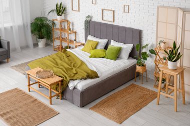 Yatak odasının içinde büyük yatak odası, raf ünitesi, bank ve bitkiler var.