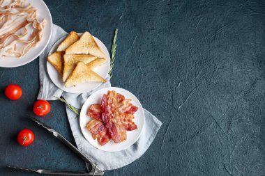 Çiğ pastırmalı yemekler, kızarmış pastırma ve siyah arka planda tost. Üst görünüm