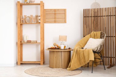 Oturma odasının içinde lamba, çaydanlık, çay ve koltuk olan kahve masası.