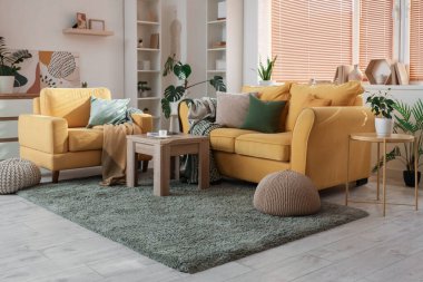 Rahat sarı kanepesi, koltuğu ve sehpası olan şık bir oda.