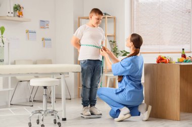 Kadın beslenme uzmanı, klinikte kilolu bir çocuğun karnını tartıyor. Diyet kavramı