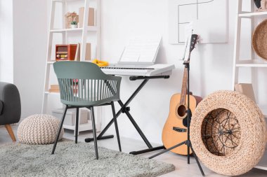 Sentezleyici, gitar ve raf üniteleriyle oturma odasının içinde.