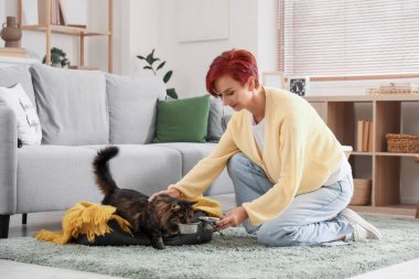 Güzel, mutlu, olgun bir kadın tatlı kedisini evde besliyor.