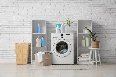 Çamaşır makinesi, deterjan şişeleri ve sepetlerle dolu bir çamaşır odası.