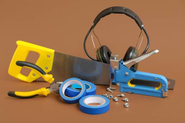 Kahverengi arka planda marangoz aletleri ve işitme koruma kulaklıkları