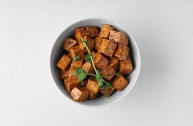 Beyaz arka planda kızarmış tofu peyniri ve mikro yeşil tabakla.