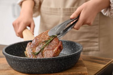 Mutfakta leziz biftek kızartan bir kadın.