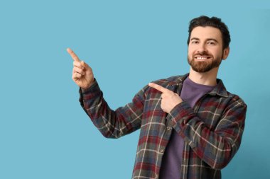 Genç adam mavi arka plandaki bir şeyi işaret ediyor.