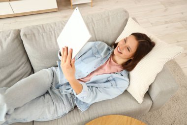 Tablet bilgisayar evde kanepede kullanan genç kadın