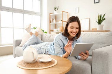 Tablet bilgisayar evde kanepede kullanan genç kadın