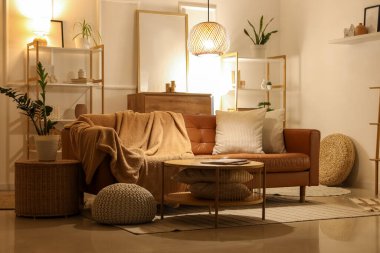 Oturma odasının içinde kahverengi kanepe, raf üniteleri ve akşam lambaları var.