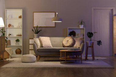 Gri kanepe, masa ve gece lambasıyla oturma odasının içinde.