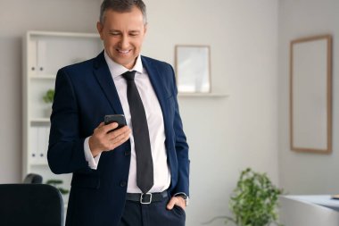 Ofiste cep telefonuyla konuşan yakışıklı, olgun iş adamının portresi.