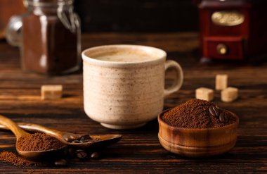 Bir fincan espresso, kahve tozu ve şeker ile ahşap masa, yakın plan.