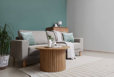 Gri kanepesi ve ahşap masası olan şık bir oturma odası.