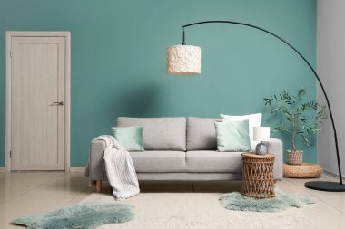 Gri kanepesi, masası ve lambası olan şık bir oturma odası.