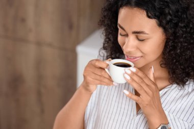 Genç Afro-Amerikalı kadın mutfakta kahve içiyor, yakın plan.