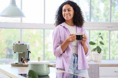 Genç Afro-Amerikalı kadın mutfakta bir fincan kahveyle